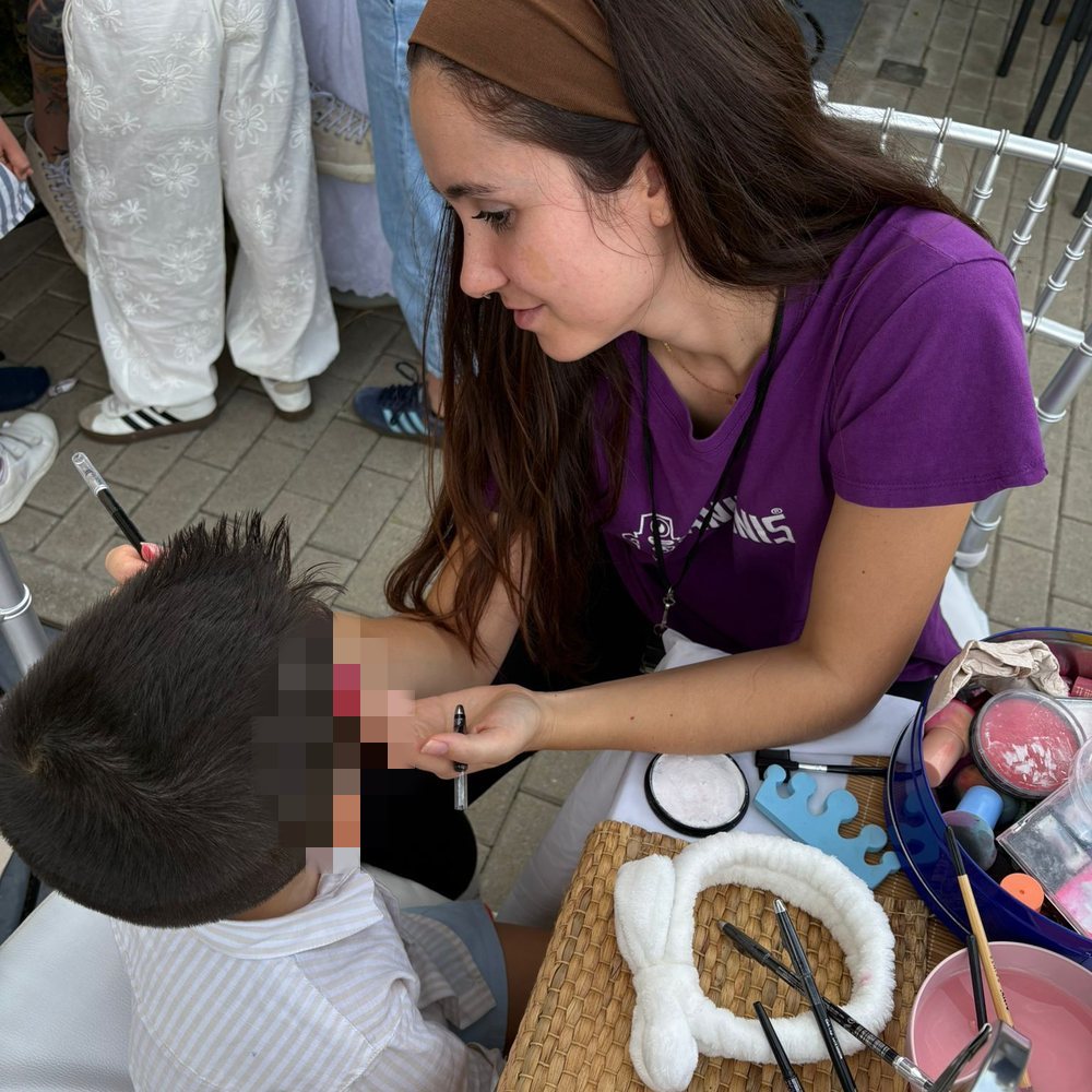 Elisa pintando la cara a un niño en una actividad infantil